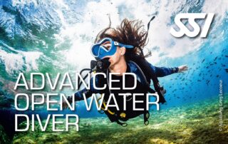 Eine Taucherin mit Ausrüstung schwimmt unter Wasser in einer klaren Umgebung. Das Bild zeigt das Brevet für den SSI Advanced Open Water Diver.