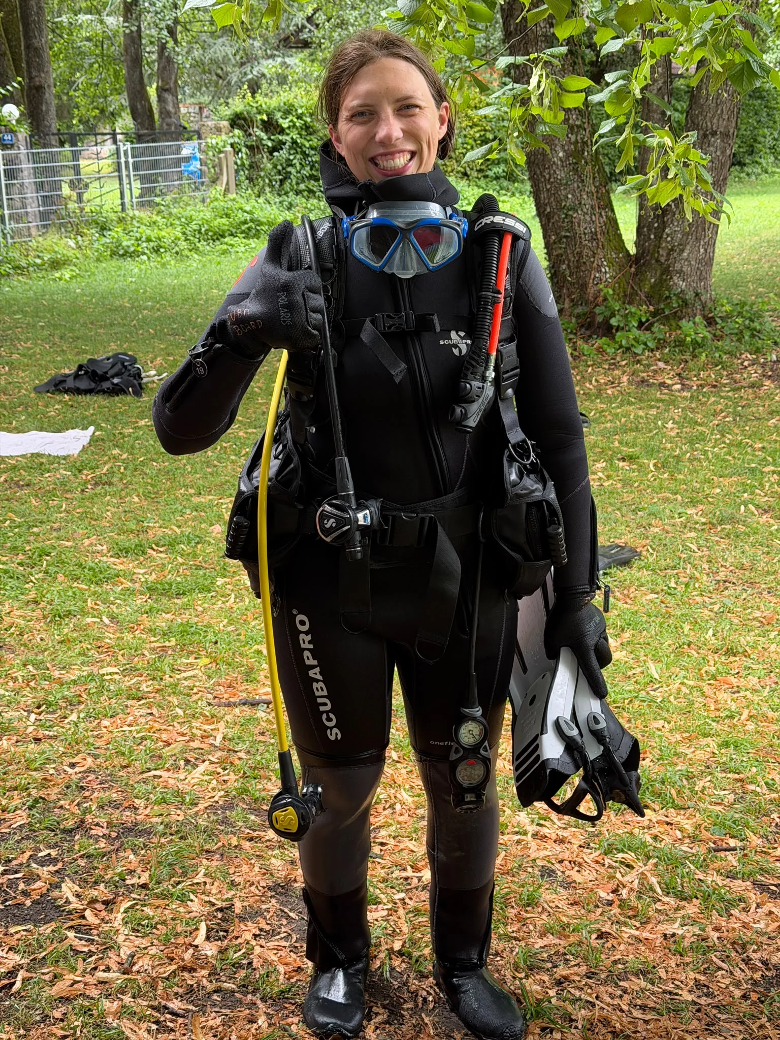 Lächelnde Taucherin im schwarzen Tauchanzug am Attersee Eine lächelnde Taucherin steht im schwarzen Tauchanzug mit Maske, Flossen und Atemregler auf einer Wiese am Attersee.