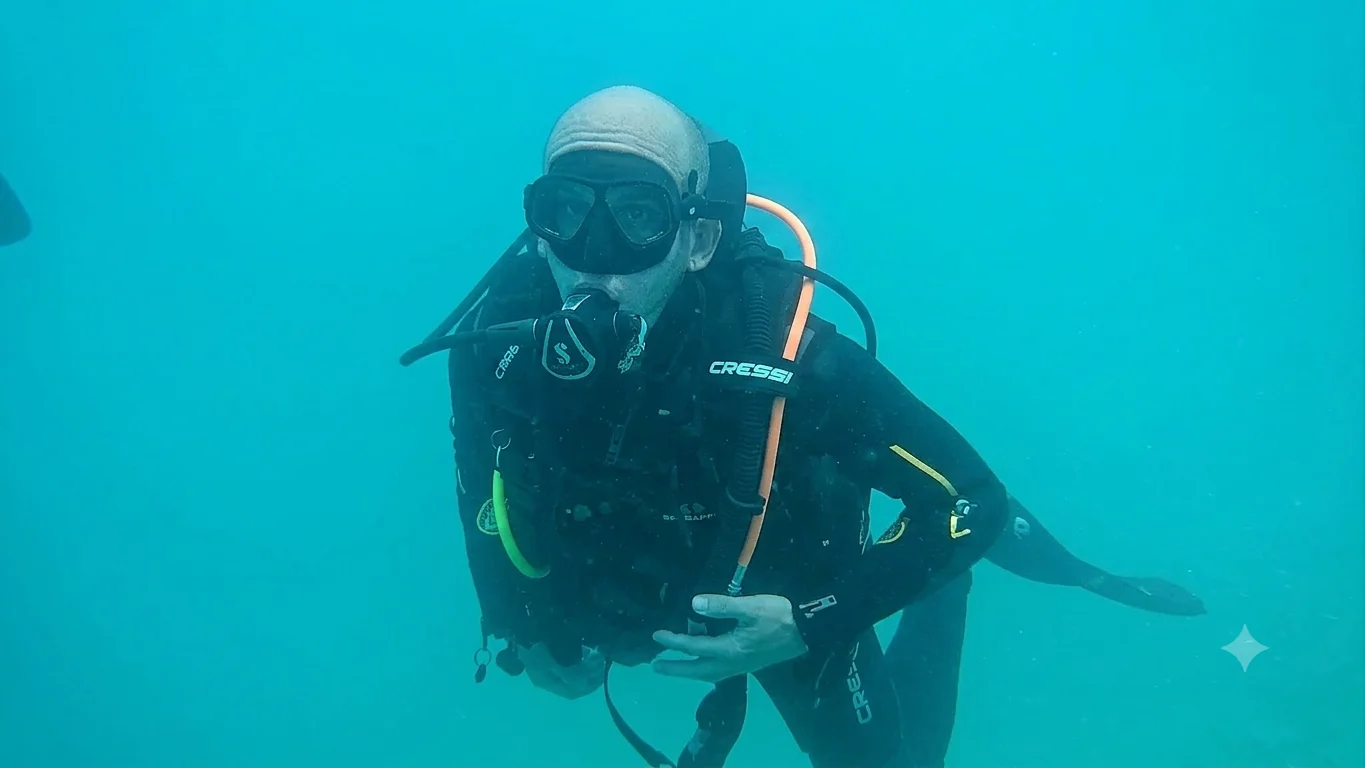 Ein Taucher in schwarzer Ausrüstung mit Cressi-Atemregler schwebt im türkisfarbenen Wasser des Attersees.