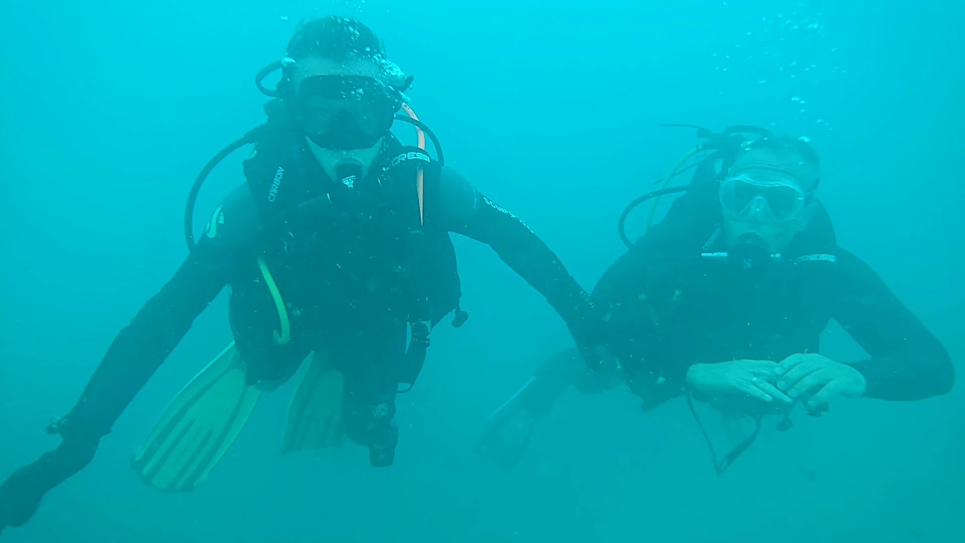Zwei Taucher unter Wasser beim Freiwassertauchgang am Attersee Zwei Taucher mit Tauchermasken und Pressluftflaschen bewegen sich gemeinsam unter Wasser im klaren, blaugrünen See.