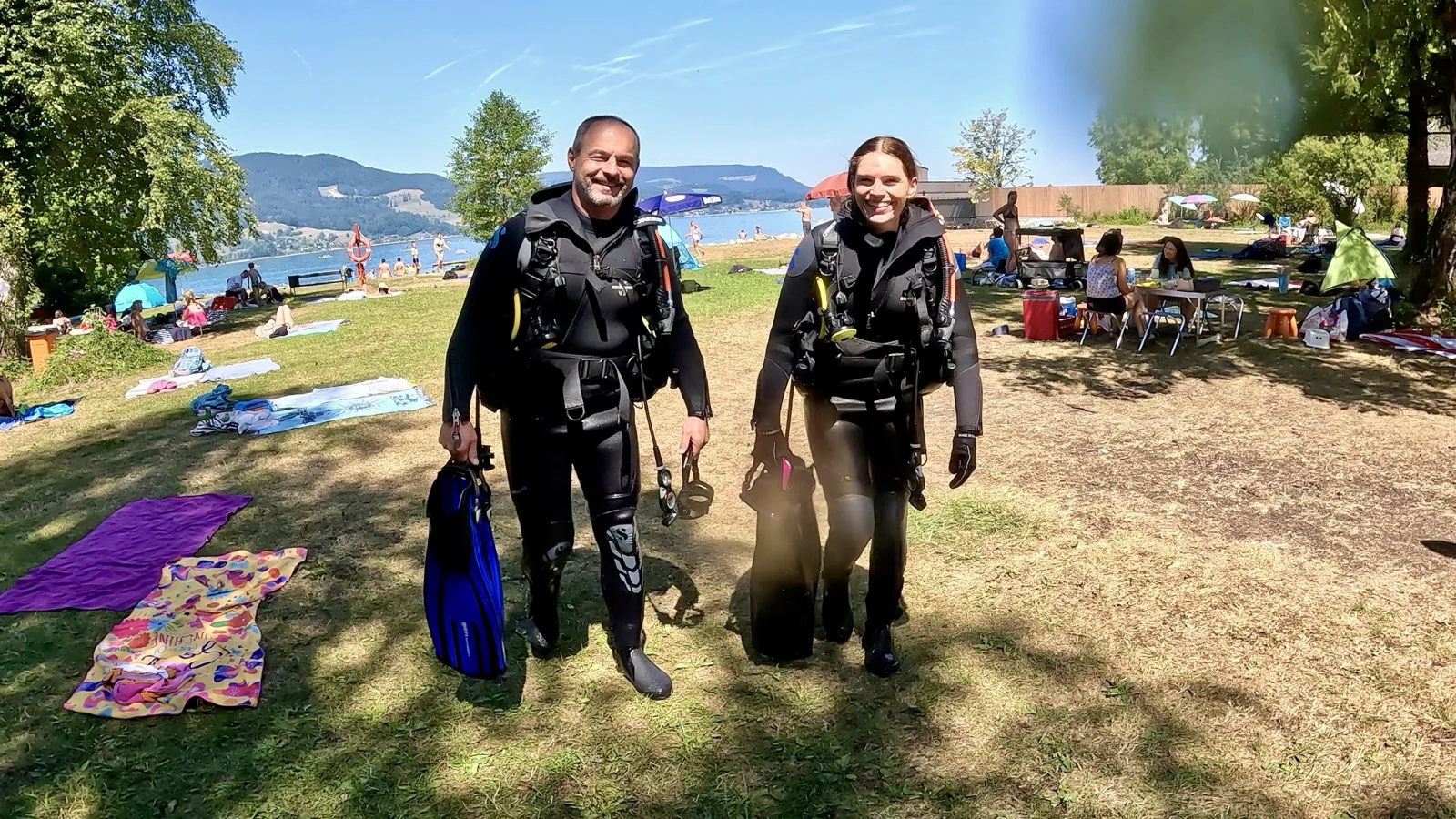 GPTempDownload-14 Ronja und Mario stehen am Ufer des Attersees in schwarzer Tauchausrüstung, bereit für ihren Open-Water-Diver-Kursabschluss.