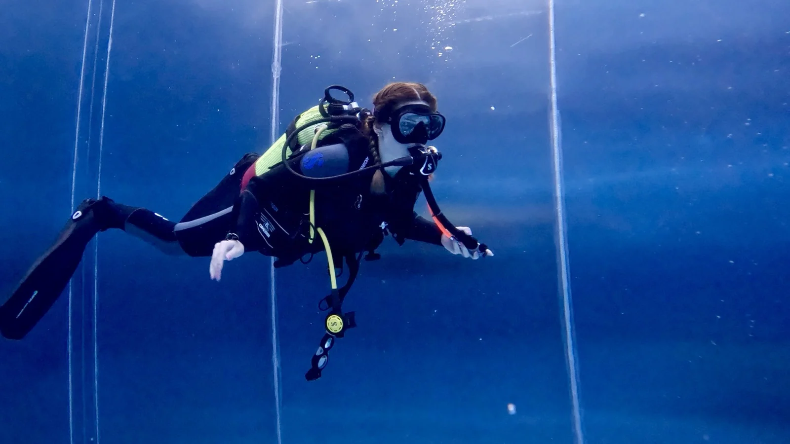 GPTempDownload-3 Eine Taucherin schwebt mit Atemregler und Flossen im Poolwasser während eines Open-Water-Diver-Kurses.