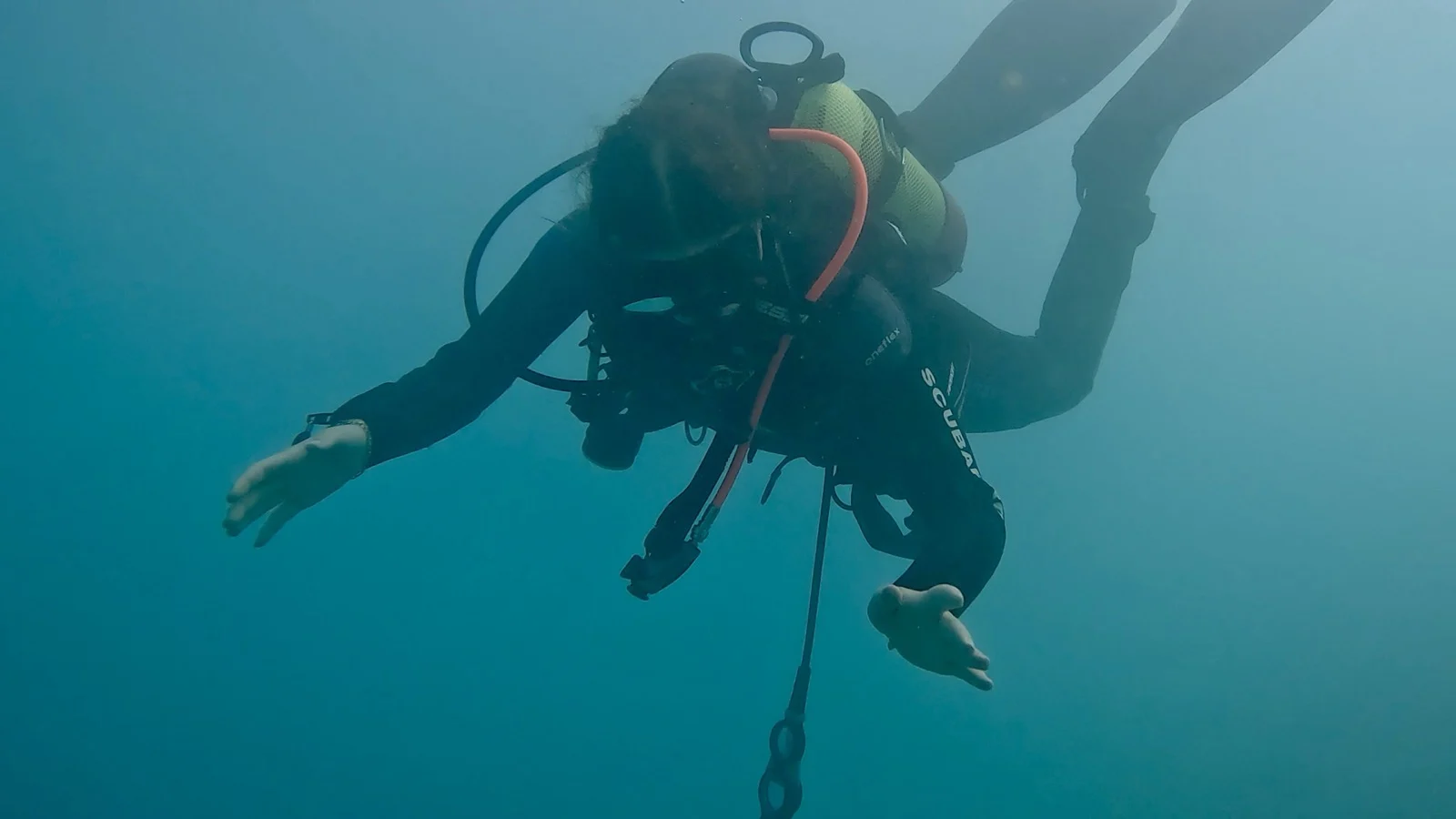 Open Water Diver am Attersee, Unterwassertraining im grünlichen Wasser Ein Taucher in Taucherausrüstung schwebt unter Wasser im grünlichen, trüben Attersee und streckt die Hände nach vorn.