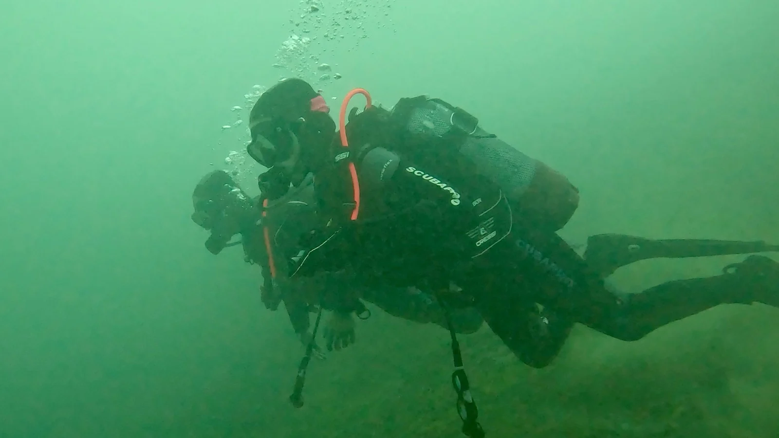Ronja und Mario beim Tauchen im grünen Wasser am Attersee Zwei Taucher gleiten durch grünes, trübes Wasser und absolvieren Übungen unter Wasser am Attersee.